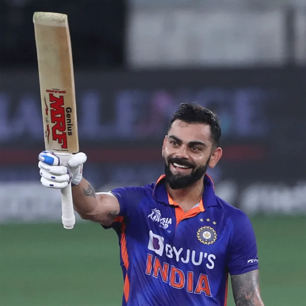 Virat Kohli celebrating a century, raising his bat during an international match in the chase for 100 centuries
